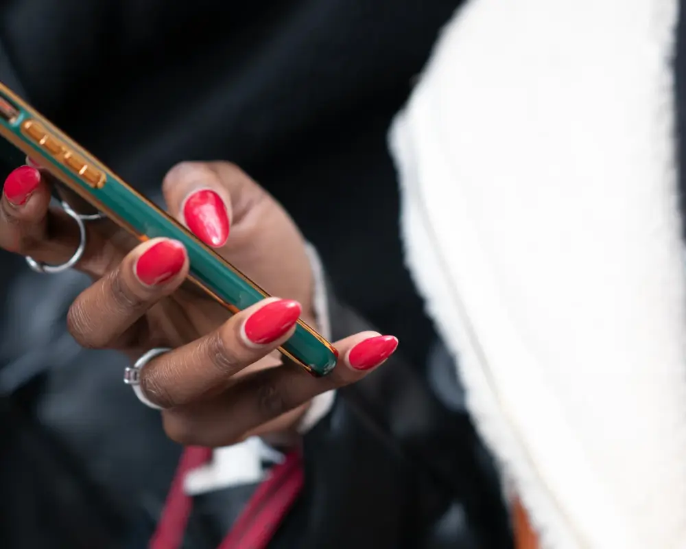 Hand with red nails holding a green smartphone